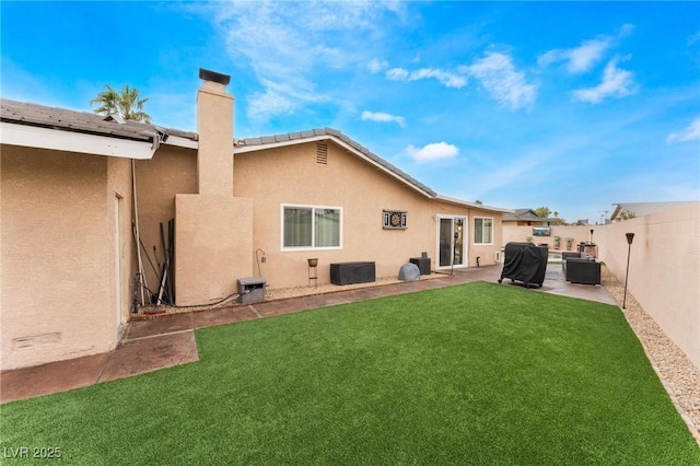 back of property with stucco siding, a patio, a fenced backyard, a yard, and a chimney