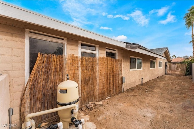 view of side of property featuring stucco siding and fence