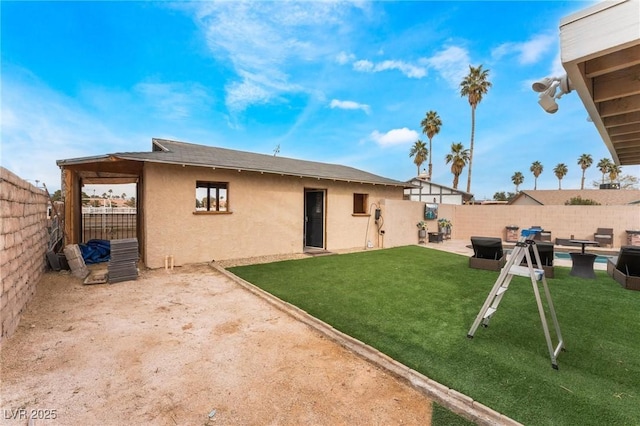 back of house featuring a yard, stucco siding, a patio, and a fenced backyard