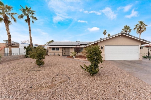 ranch-style house featuring stucco siding, a garage, solar panels, and concrete driveway