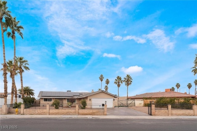 single story home featuring a fenced front yard, roof mounted solar panels, a garage, and driveway