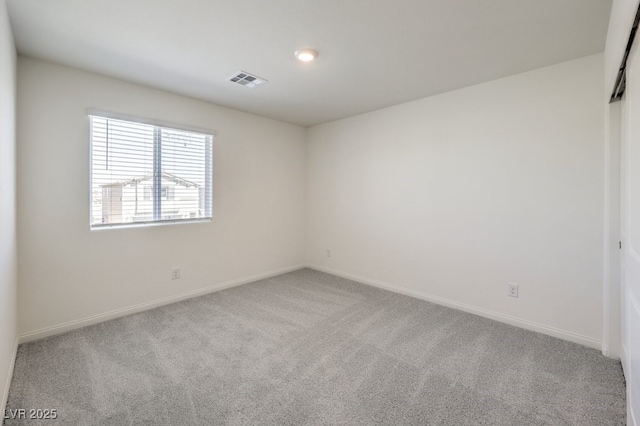 carpeted spare room featuring visible vents and baseboards