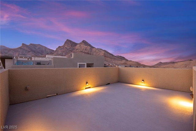 patio terrace at dusk with a mountain view and a balcony