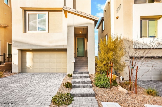 view of front of property with stucco siding, an attached garage, and decorative driveway