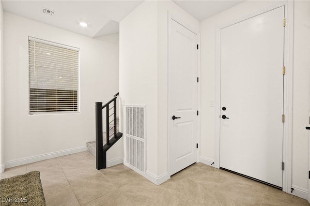 hall featuring light tile patterned floors, visible vents, stairway, and baseboards