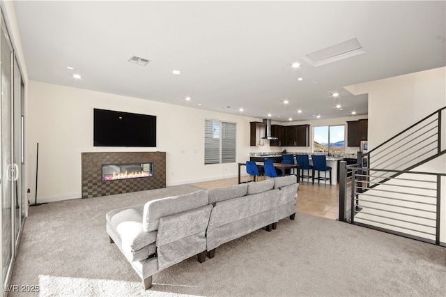 living area with recessed lighting, a fireplace, visible vents, and light carpet