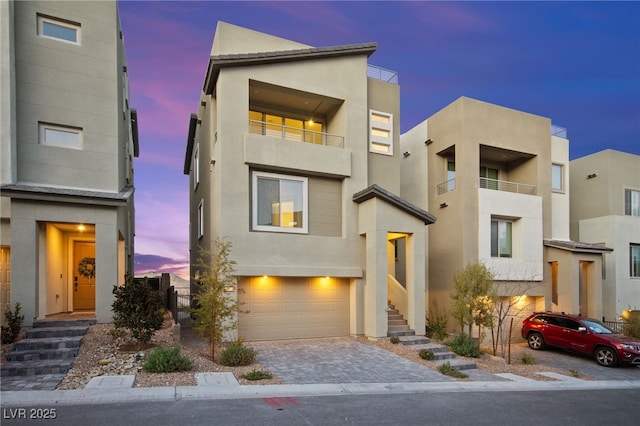 contemporary house featuring decorative driveway, a garage, and stucco siding