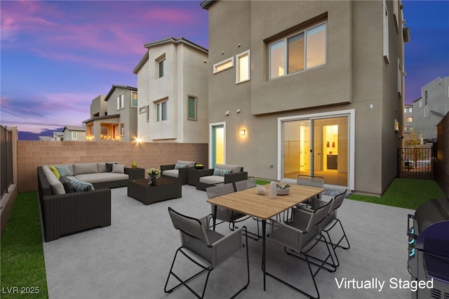 patio terrace at dusk featuring outdoor dining space, a fenced backyard, and an outdoor hangout area