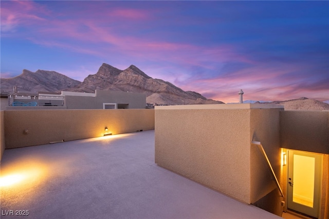 patio terrace at dusk featuring a balcony and a mountain view