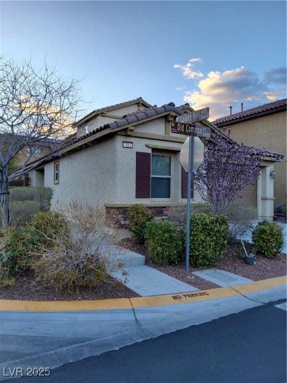 view of side of home with a tile roof and stucco siding