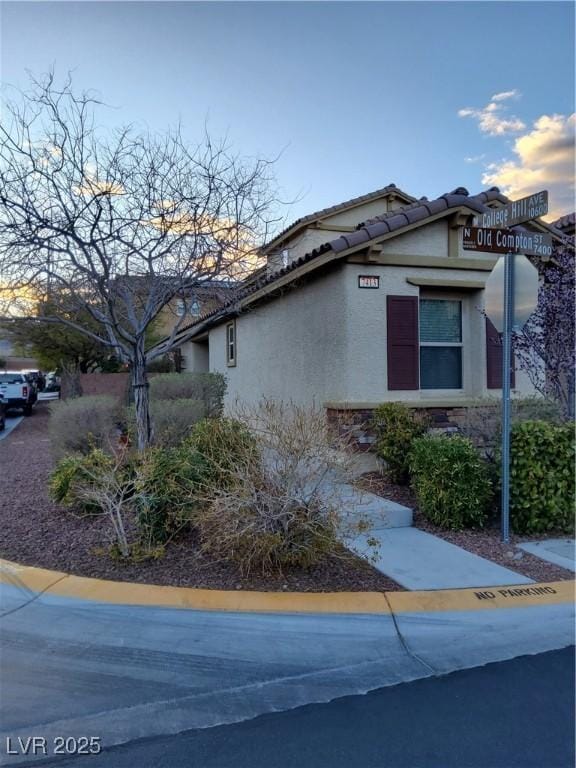 view of property exterior with a tile roof and stucco siding