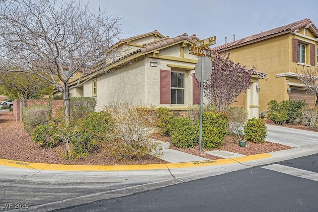 view of front of house with stucco siding, concrete driveway, and a tiled roof