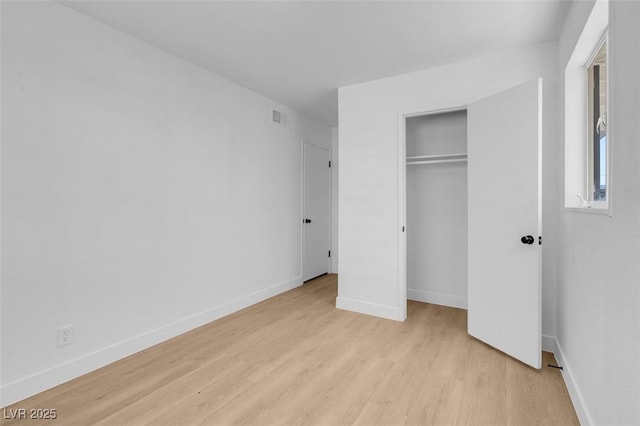 unfurnished bedroom with light wood finished floors, visible vents, a closet, and baseboards