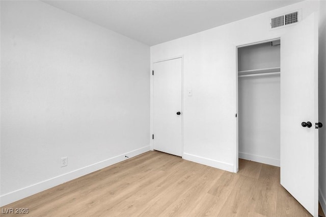 unfurnished bedroom featuring light wood-type flooring, visible vents, baseboards, and a closet