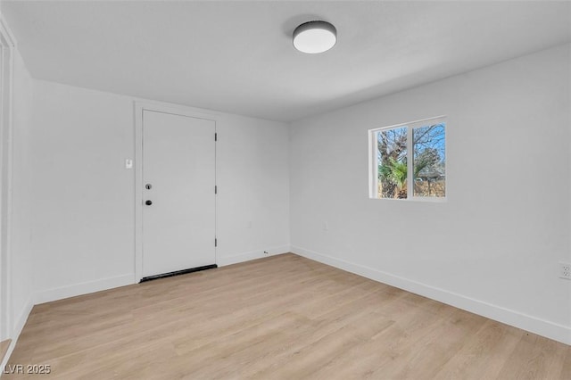 spare room with baseboards and light wood-style floors