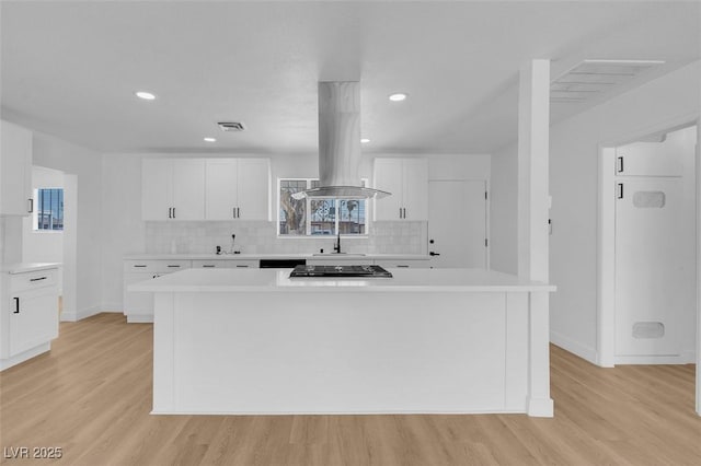 kitchen with visible vents, light wood-style flooring, island exhaust hood, and light countertops