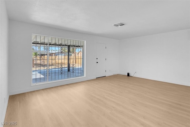 unfurnished room with visible vents, light wood-style flooring, and baseboards