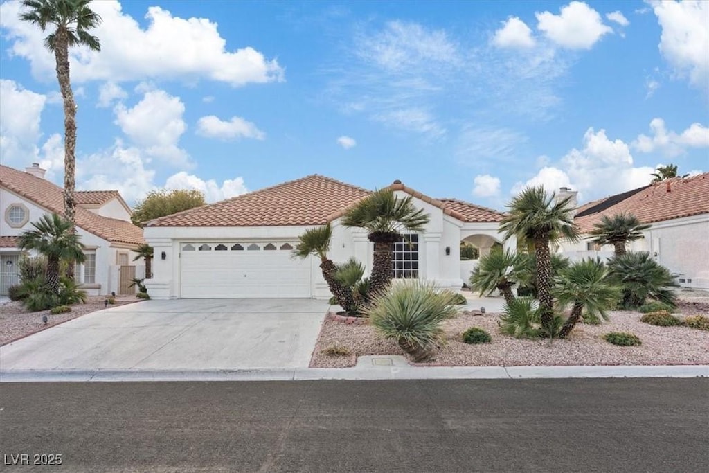 mediterranean / spanish-style home with a garage, a tile roof, driveway, and stucco siding