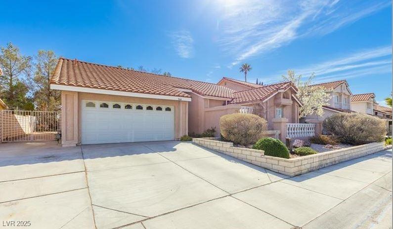 view of front of house with stucco siding, concrete driveway, a tile roof, and a garage