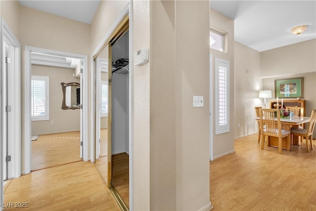 corridor featuring light wood-style flooring and baseboards