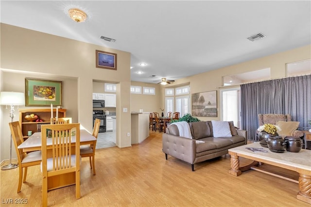 living room featuring light wood-type flooring, visible vents, and ceiling fan