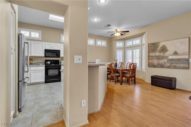 kitchen with a ceiling fan, visible vents, black appliances, white cabinets, and light wood-style floors