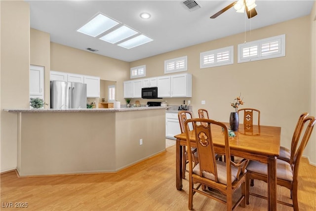 dining area featuring a skylight, visible vents, light wood-style flooring, and a ceiling fan