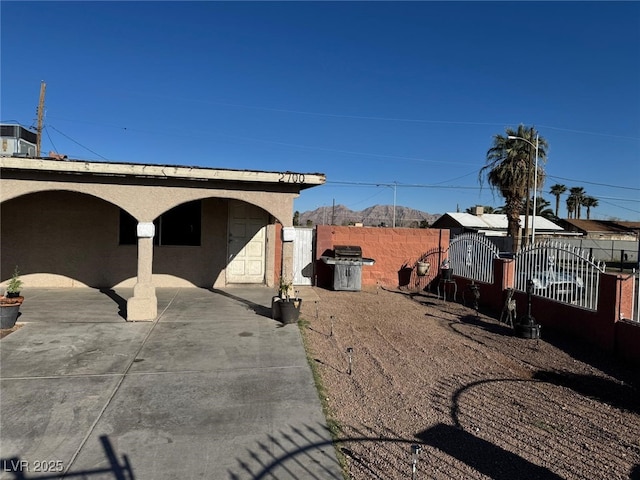 view of side of home with a gate, central AC unit, stucco siding, fence private yard, and a patio area