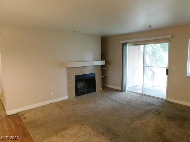 unfurnished living room with built in features, visible vents, baseboards, a tiled fireplace, and carpet flooring