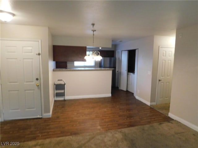 kitchen with dark wood-style floors, baseboards, a peninsula, decorative light fixtures, and a notable chandelier