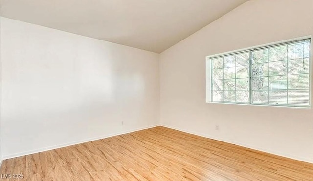 unfurnished room featuring baseboards, light wood-style flooring, and vaulted ceiling