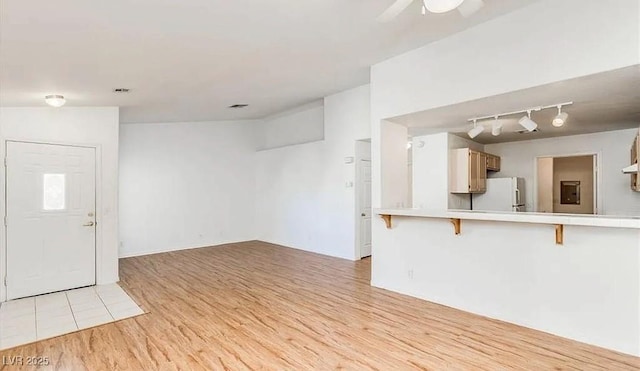 unfurnished living room featuring rail lighting, light wood-style flooring, and a ceiling fan