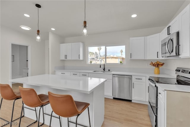 kitchen with light countertops, a kitchen breakfast bar, appliances with stainless steel finishes, and a sink