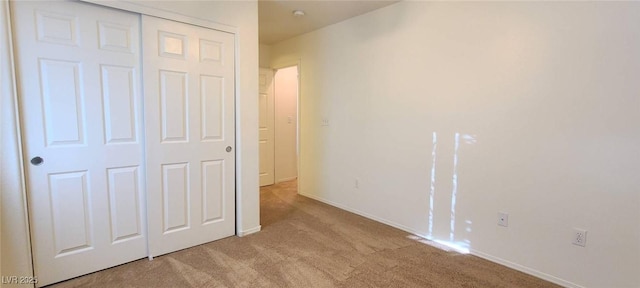 unfurnished bedroom with baseboards, a closet, and carpet floors