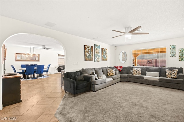 living area featuring arched walkways, ceiling fan with notable chandelier, and light tile patterned flooring