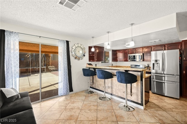 kitchen with visible vents, a kitchen bar, light countertops, appliances with stainless steel finishes, and a peninsula