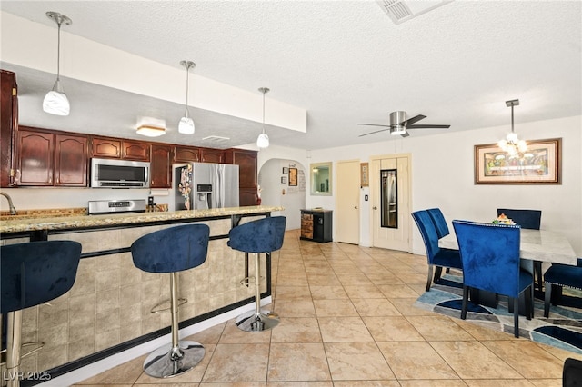 kitchen with visible vents, arched walkways, stainless steel appliances, light countertops, and a textured ceiling