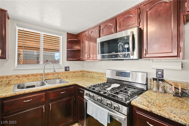 kitchen with a sink, a textured ceiling, light stone countertops, and stainless steel appliances