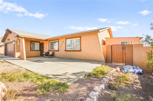 view of front of home with a gate, a garage, and stucco siding