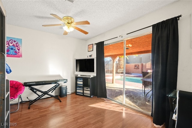 interior space featuring a textured ceiling, ceiling fan, and wood finished floors