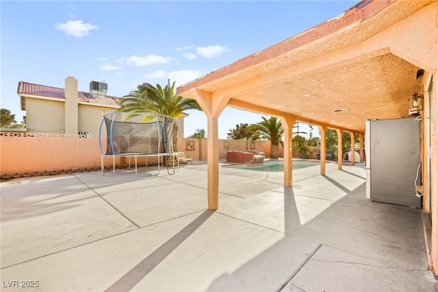 view of patio with a fenced backyard, cooling unit, and a trampoline