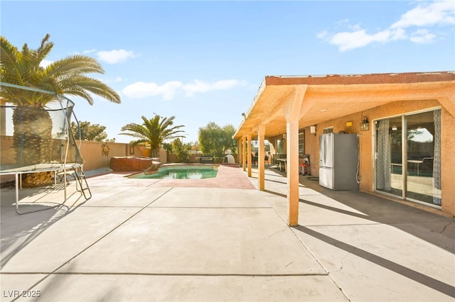 view of patio with a fenced in pool, a trampoline, and a fenced backyard