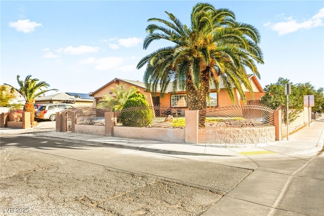 view of front of house with a gate, a fenced front yard, driveway, and stucco siding