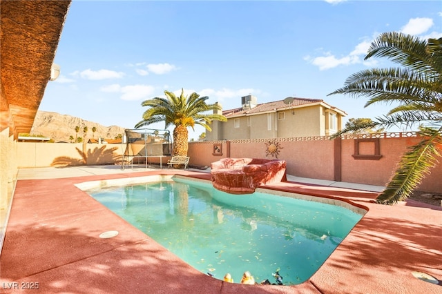 view of swimming pool with a patio, a trampoline, a fenced backyard, a mountain view, and a fenced in pool