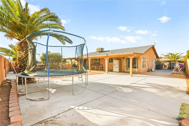 exterior space featuring a gate, a trampoline, and fence