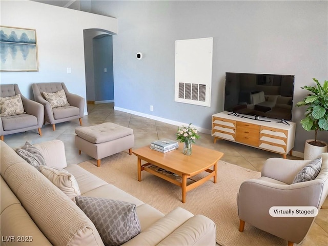 living area with visible vents, light tile patterned floors, baseboards, and arched walkways