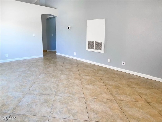 tiled spare room with baseboards and arched walkways