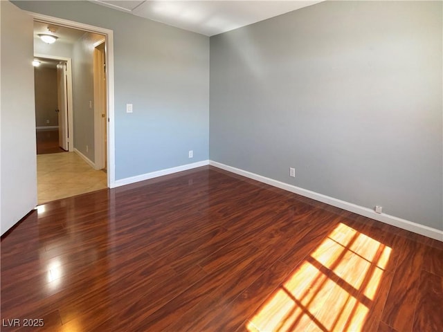 unfurnished room with baseboards and wood finished floors