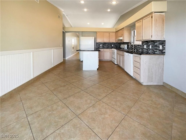 kitchen with white appliances, arched walkways, a sink, dark countertops, and a center island