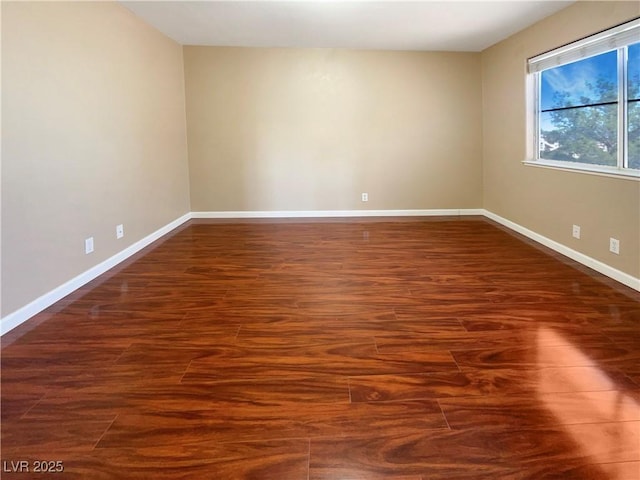 spare room featuring baseboards and wood finished floors